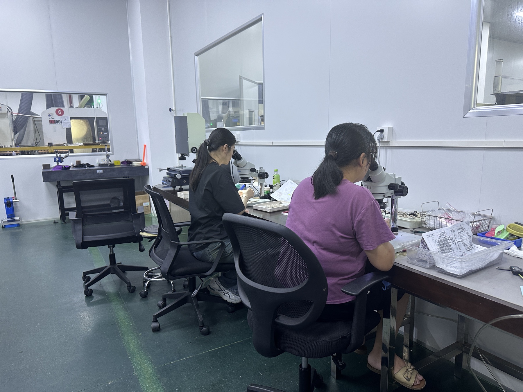 Workers inspecting small components under microscopes in the inspection room