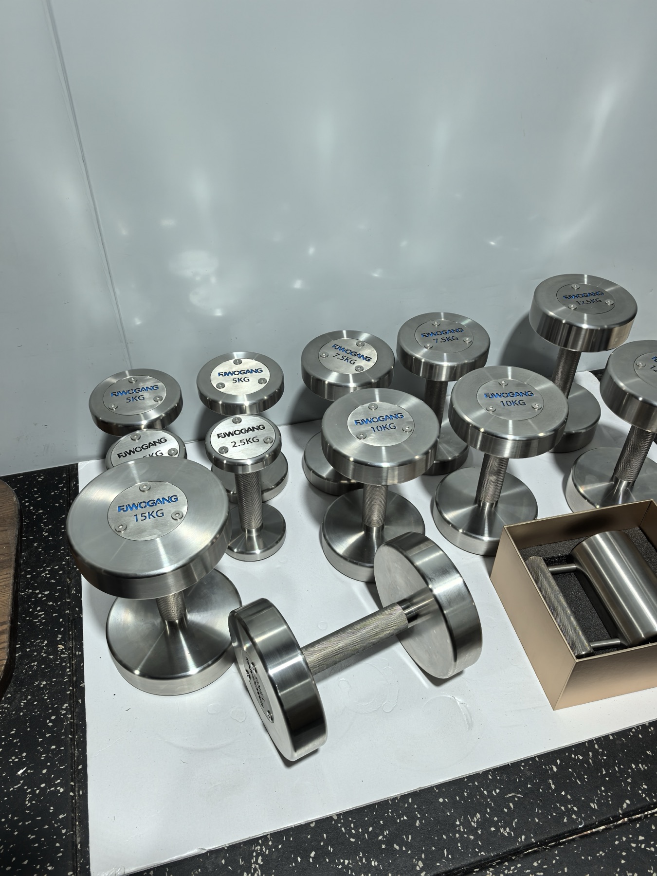 Group of finished metal dumbbells with turned cylindrical end pieces and textured connecting handles